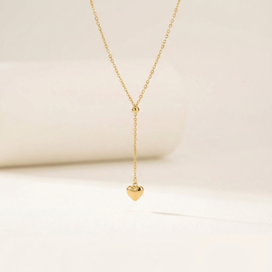 Model wearing gold Y-shape lariat necklace with heart drop on black shirt.