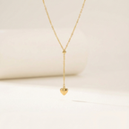 Model wearing gold Y-shape lariat necklace with heart drop on black shirt.