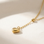 Model wearing gold Y-shape lariat necklace with heart drop on black shirt.