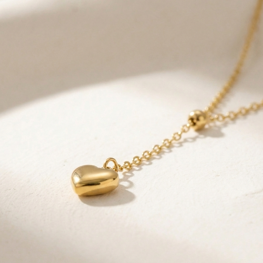 Model wearing gold Y-shape lariat necklace with heart drop on black shirt.