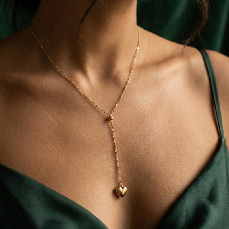 Model wearing gold Y-shape lariat necklace with heart drop on black shirt.