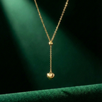 Model wearing gold Y-shape lariat necklace with heart drop on black shirt.