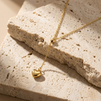 Model wearing gold Y-shape lariat necklace with heart drop on black shirt.