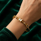 Gold cable wire bangle bracelet with black and white butterfly charms on white stone.