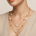 Woman wearing a layered pearl and beads 18kt gold plated necklace against a neutral background.