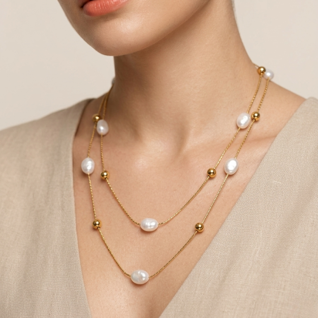 Woman wearing a layered pearl and beads 18kt gold plated necklace against a neutral background.